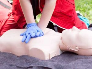 A trainer performing first aid training on a training dummy.